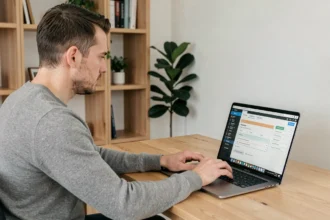 Homme assis à un bureau travaillant sur un PC portable avec une interface de configuration logicielle affichée à l'écran