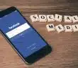 space gray iPhone 6 with Facebook log-in display near Social Media scrabble tiles